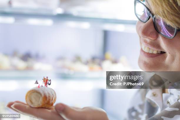 jonge vrouw houdt cannolo met miniaturen in een patisserie - pjphoto69 stockfoto's en -beelden