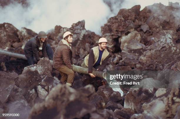 Volcano eruption on Heimaey Island in Iceland on 23 January 1973. Firefighters trying to control the lava flow by cooling it down with water so it...
