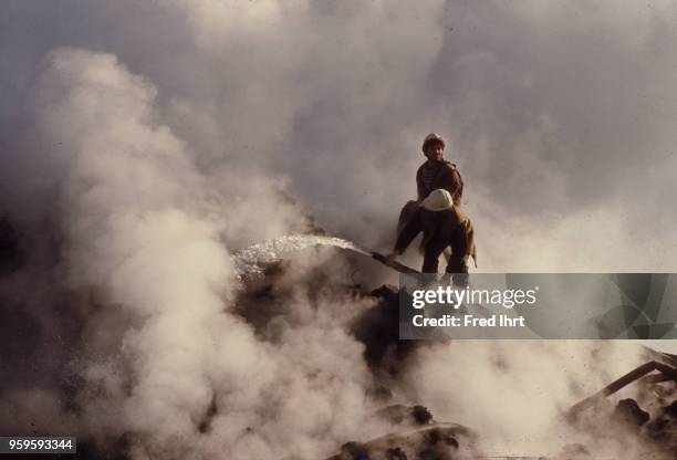 Volcano eruption on Heimaey Island in Iceland on 23 January 1973. Firefighter working on controlling the lava flow by cooling it down with water so...