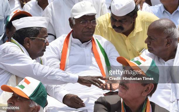 Outgoing Chief Minister of Karnataka Siddaramaiah speaks to Janata Dal leader Deve Gowda as Congress leader Mallikarjun Kharge and the leader of...