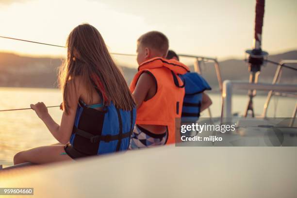 children sitting on sailboat deck while sailing - miljko stock pictures, royalty-free photos & images