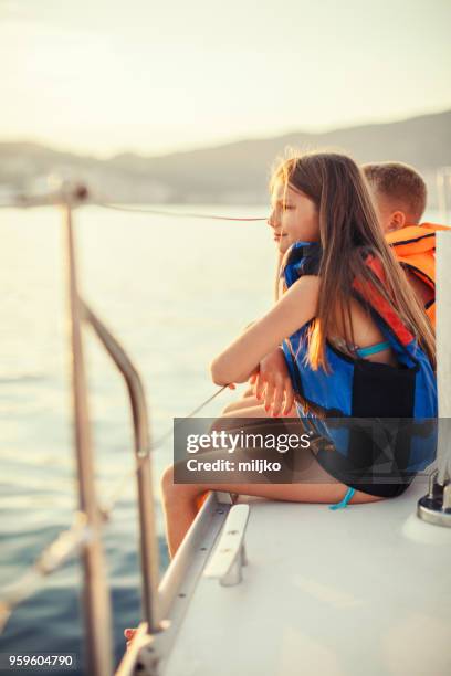 children sitting on sailboat deck while sailing - miljko stock pictures, royalty-free photos & images