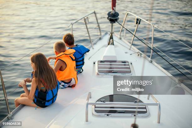 enfants assis sur le pont du voilier alors qu’il naviguait - miljko photos et images de collection