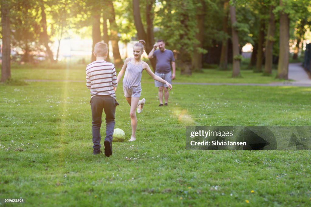 父親與男孩和女孩在公園踢足球