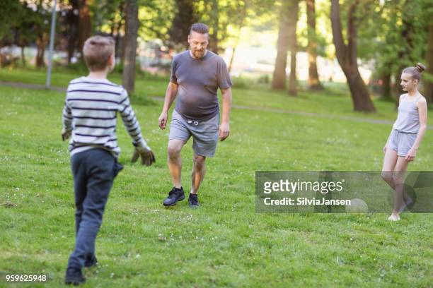 vader te voetballen met jongen en meisje in park - fussball kinder stockfoto's en -beelden