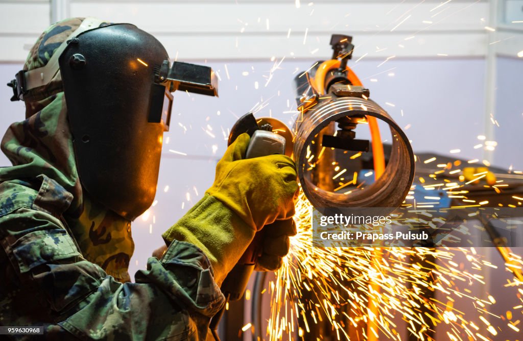 Electric wheel grinding on steel structure in factory