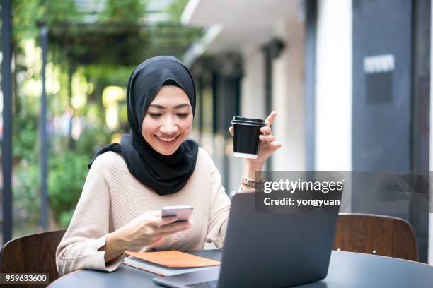 smiling malaysian girl using her smartphone - yongyuan stock pictures, royalty-free photos & images