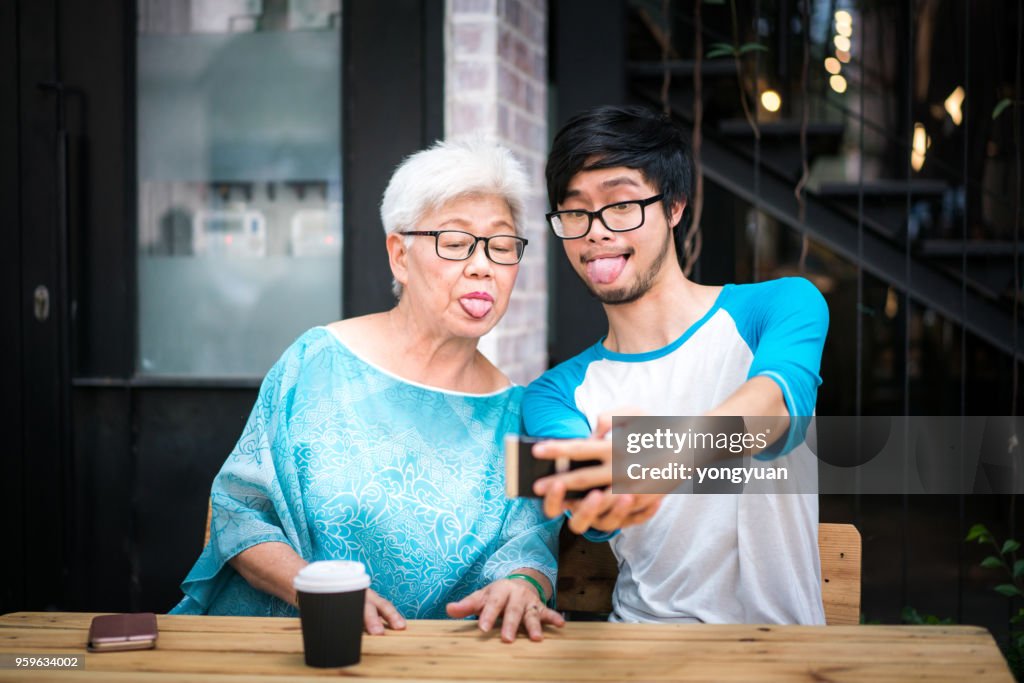 Young man taking a funny selfie with his grandmother