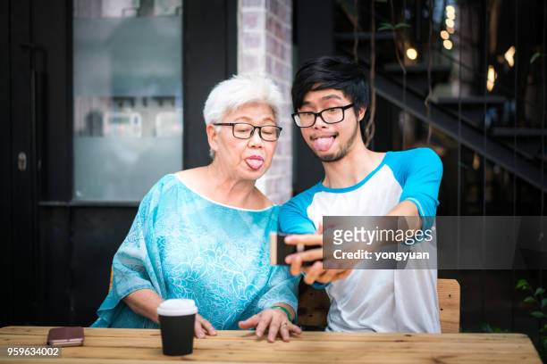 young man taking a funny selfie with his grandmother - yongyuan stock pictures, royalty-free photos & images