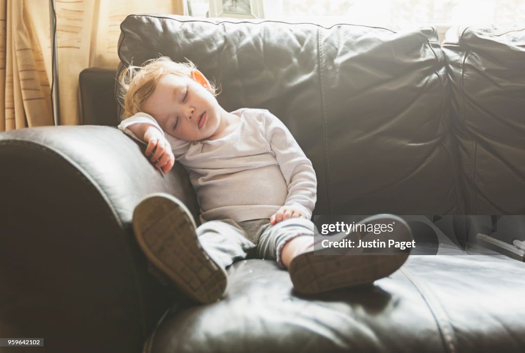 Young baby girl falls asleep on sofa