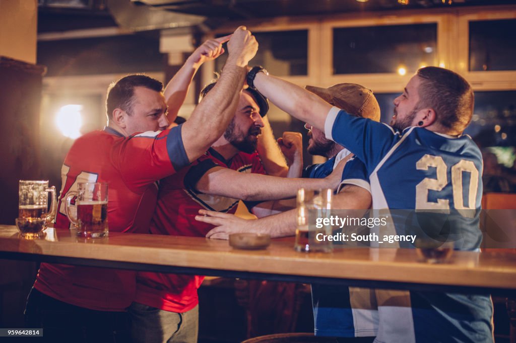 Grupo de hombres que luchan en bar deportes
