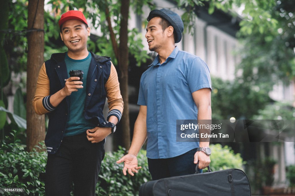 2 malay males wearing hat,  talking and walking on the street