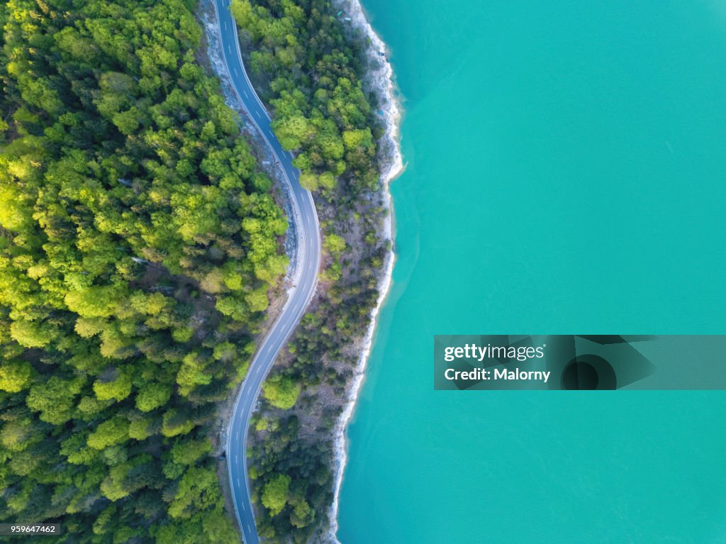 Aerial view on turquoise Lake Sylvenstein and forest with road on the bay. Germany, Bavaria, Lake Sylvenstein