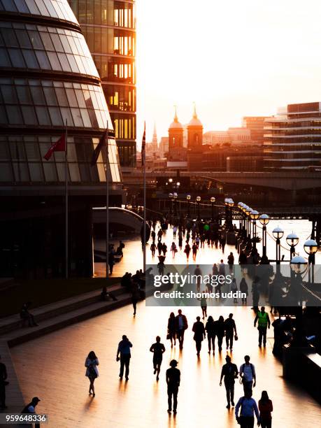 Tourists and commuters in London Riverbank against sunset sky