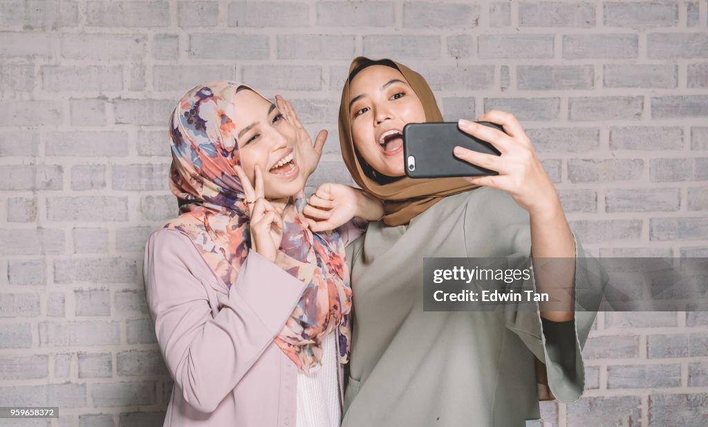 Malayo 2 mujeres que se divierten haciendo selfie con su teléfono con cámara