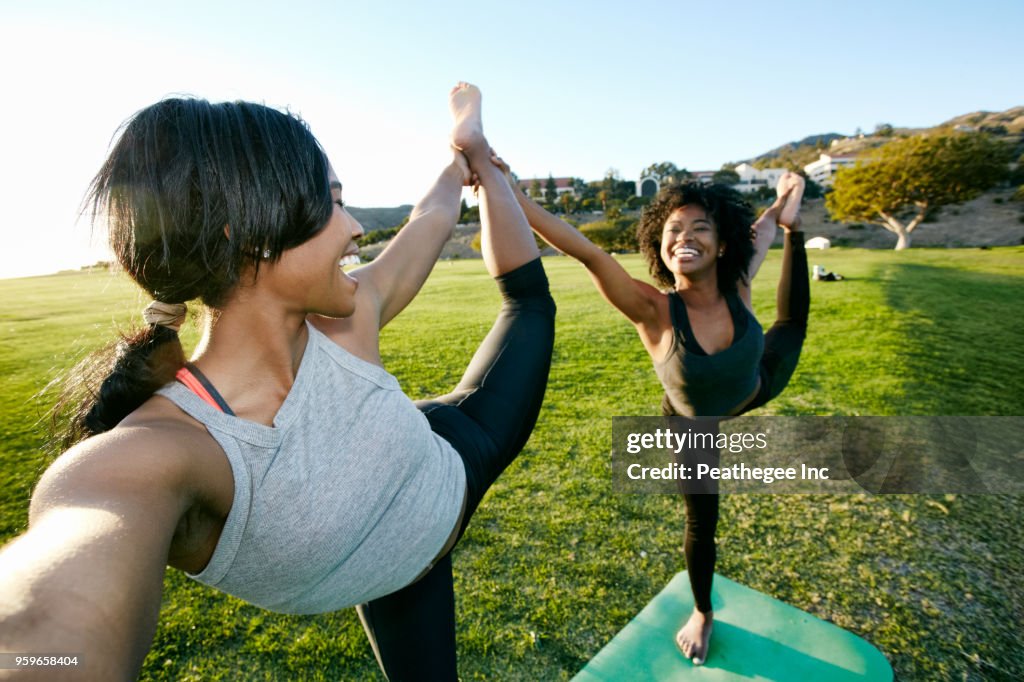 Women doing yoga together in green field