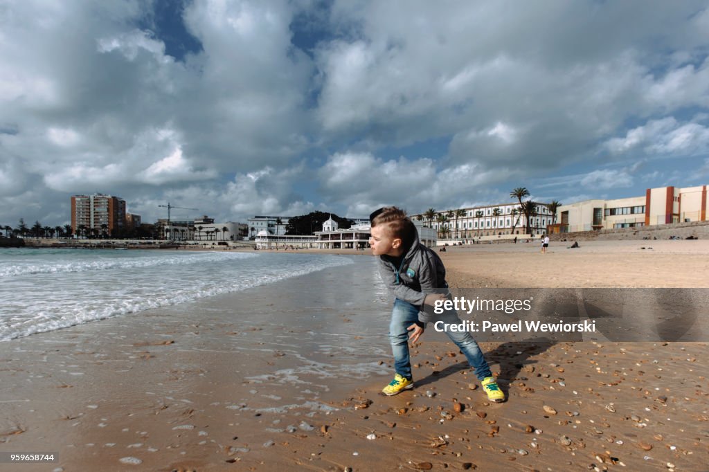 Boy throwing rocks into sea