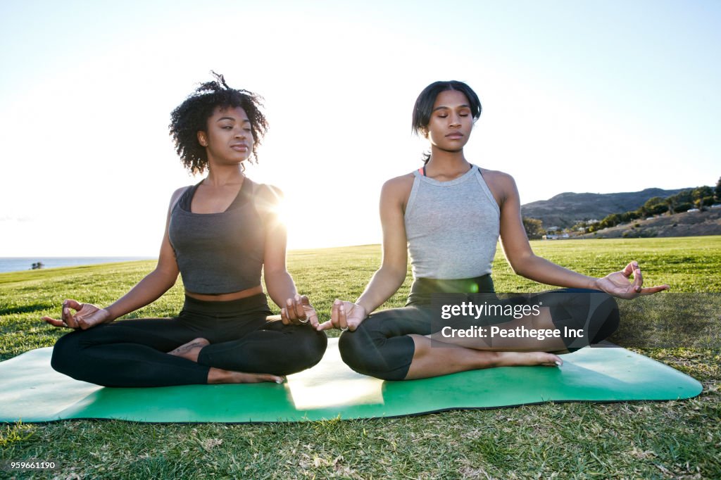 Women doing yoga together in green field