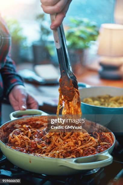 preparing tagliatelle pasta with vegan bolognese and bella lodi cheese - tagliatelle stock pictures, royalty-free photos & images