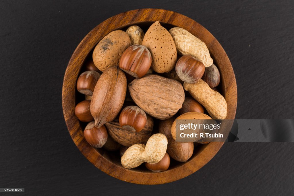 Mixed nuts in shells in a bowl a dark stone background