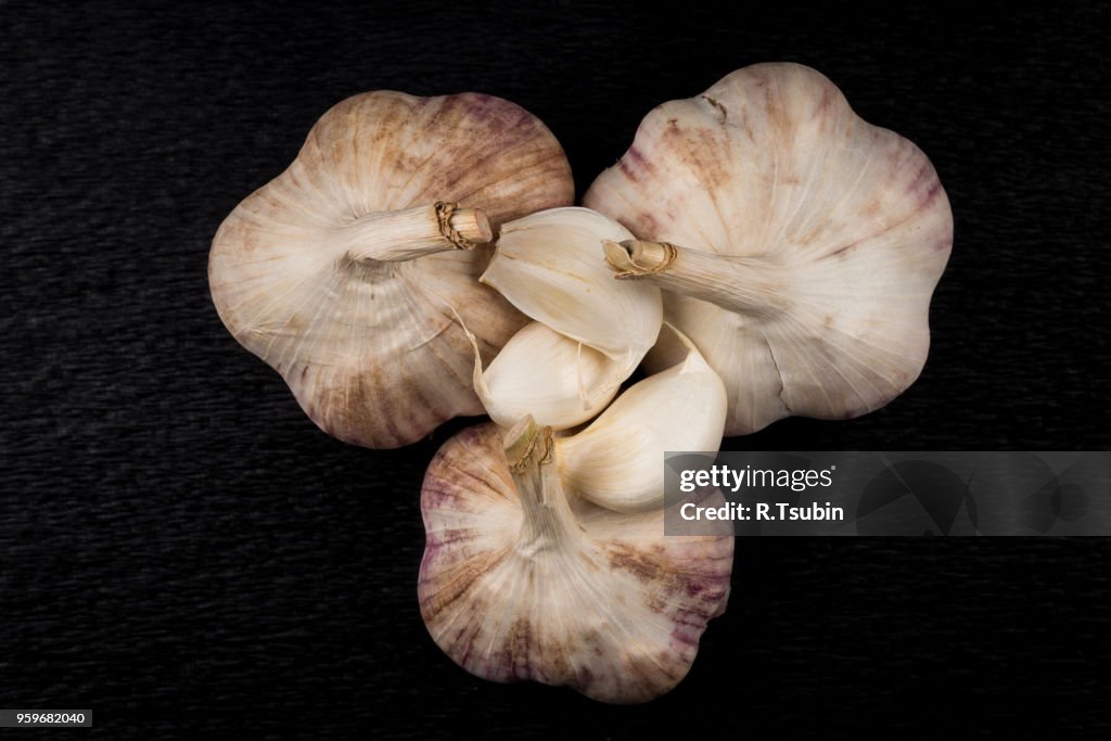 Still life photo of organic whole garlic on black stone plate