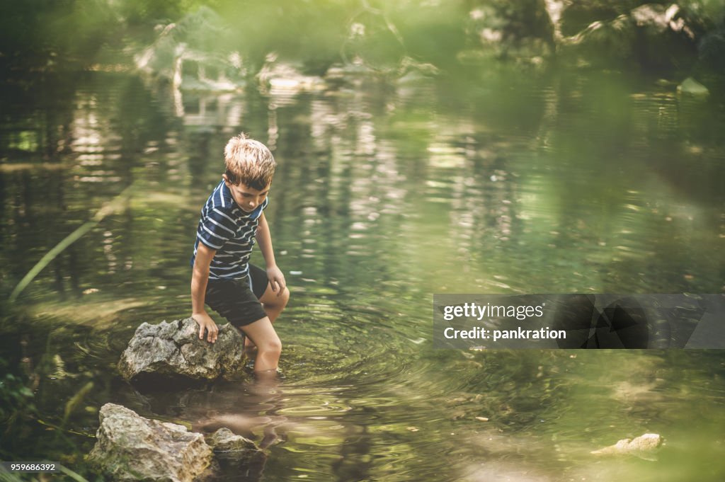 Jongen met een avontuur door te lopen In het meer bewonderen een prachtig Scenic bos