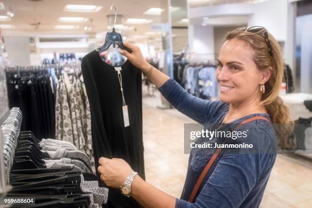 reife frau in einem bekleidungsgeschäft lächelnd - ecuadorianischer abstammung stock-fotos und bilder
