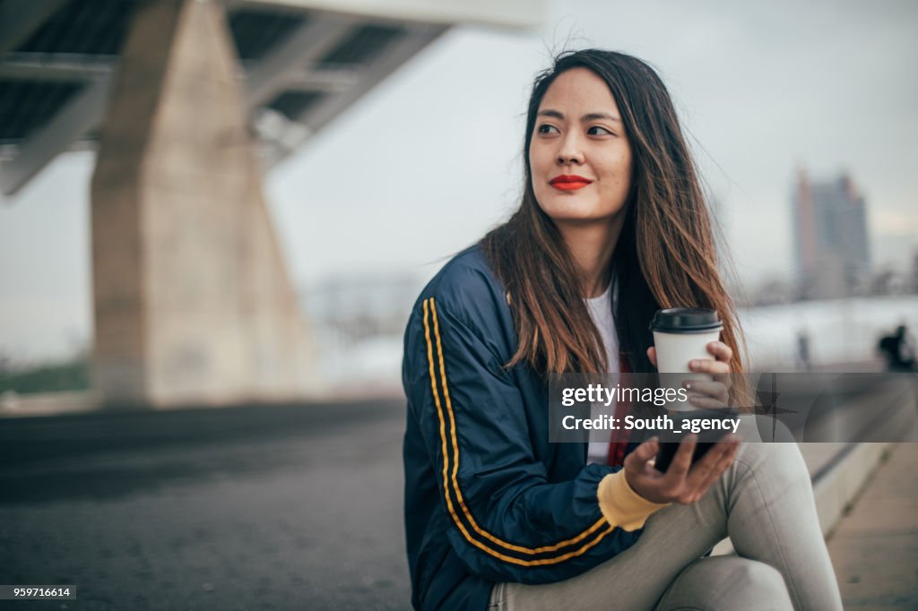 年輕的成年婦女在手機上發短信和喝咖啡