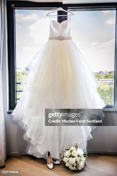 detail shot of a bride's wedding dress, shoes, and bouquet in front of a window in berlin, germany summertime - abito da sposa foto e immagini stock