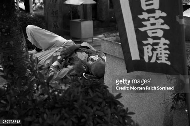 black and white shot of a local man sleeping on a street bench in tosa, japan summertime - 高松市 ストックフォトと画像