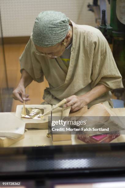 a craftsmen applies gold leaf to paper at a workshop in kanasawa, japan summertime - kanazawa stock pictures, royalty-free photos & images
