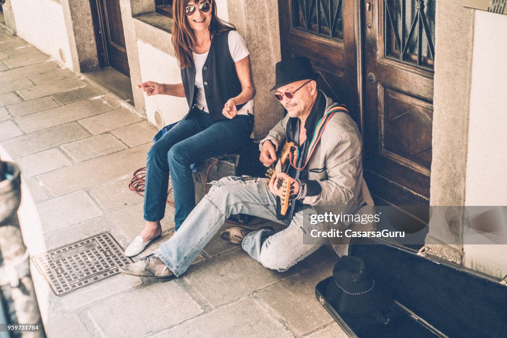 Senior homme et Mature femme Street artistes jouant de la guitare et le chant