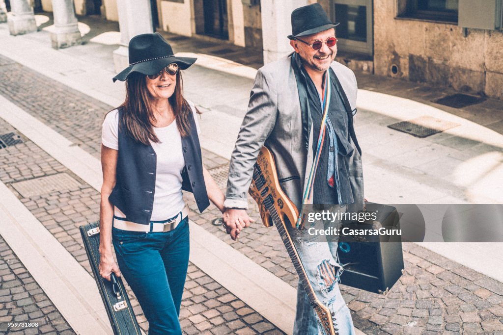 Senior Man and Mature Woman Musicians Walking on the Street and Holding Hands