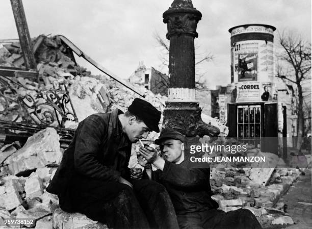 Two men smoke in the middle of ruins, in December 1948 in Berlin, as cigarettes are rare during the Berlin Blockade. On June 24 during the Cold War,...