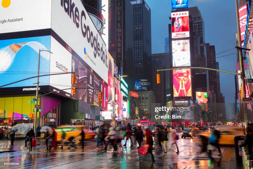 Crowd of People Crossing Street at Times Square, Rainy Day in Manhattan, New York