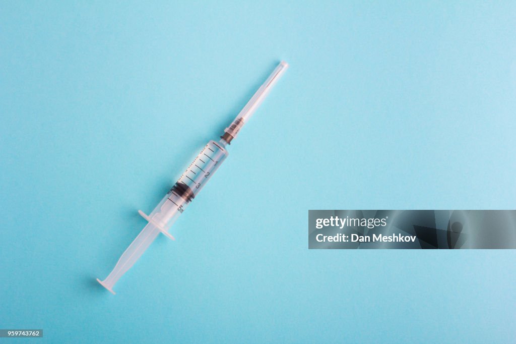 Syringe with lid on blue background