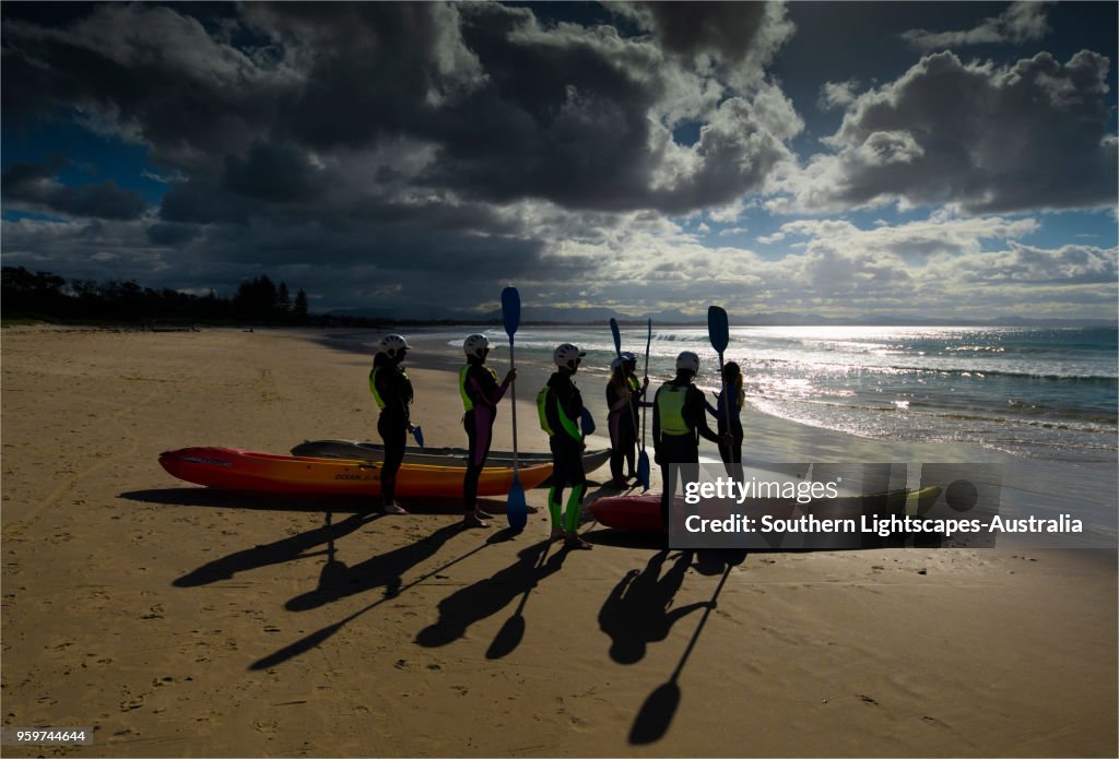 Beach scene and a group of people ready to go sea kayaking, Byron Bay, New south Wales, Australia.