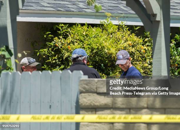 An FBI agent, right, and other officers walk through the backyard as federal agents from multiple agencies including the Orange County Sheriff...