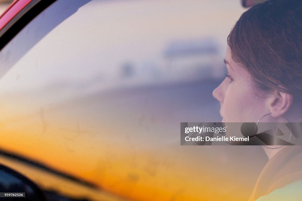 Young woman sitting in car behind glass window