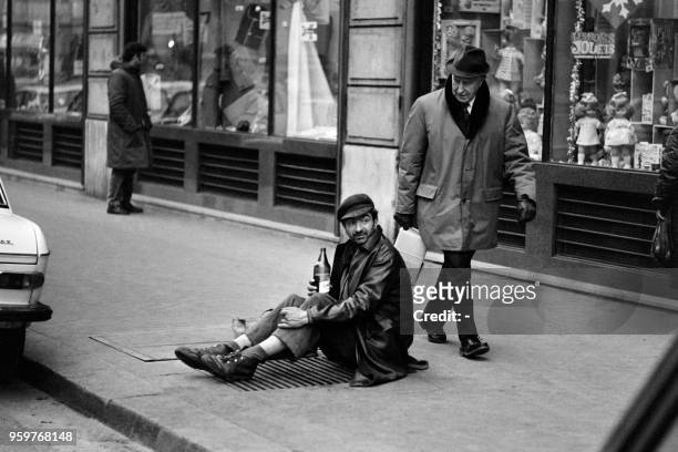 An homeless sits on an air vent to get warm during a cold period on december 1970, in Paris.