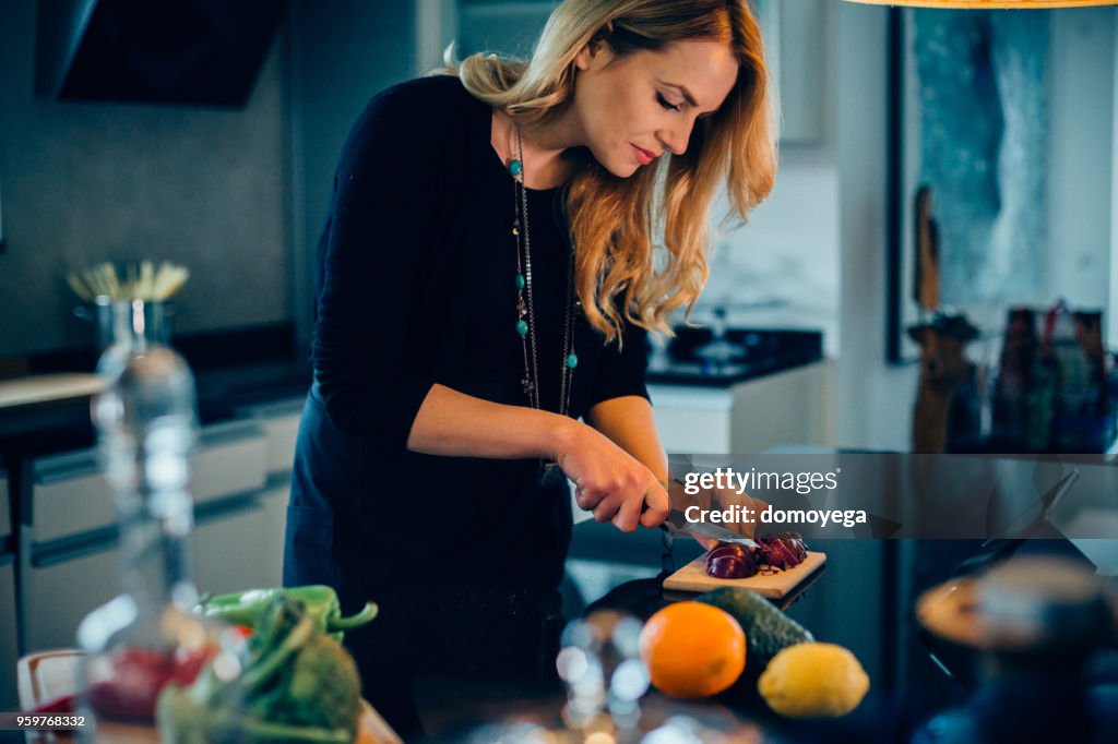 Jovem mulher prepara uma refeição saudável na cozinha e leitura receita