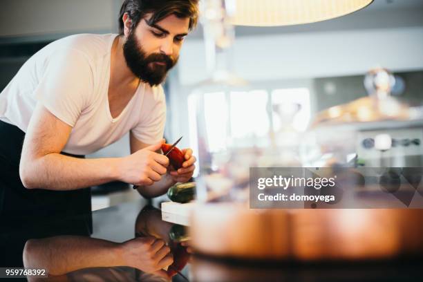 young handsome man cooking in the kitchen - cortar cebola imagens e fotografias de stock