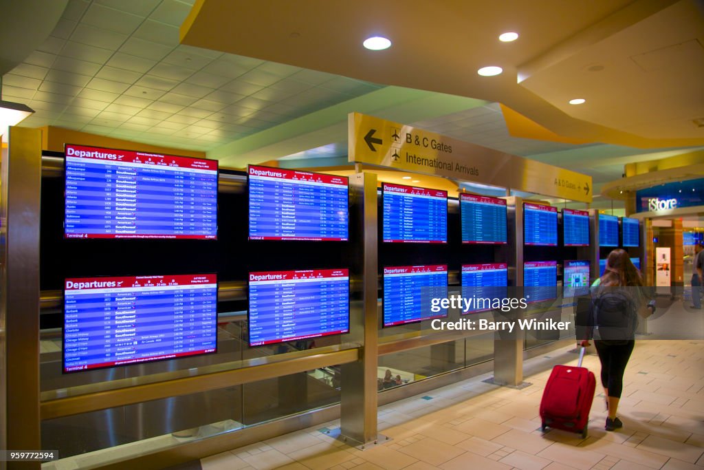 Woman walking by flight arrival/departure screens in Phoenix, AZ