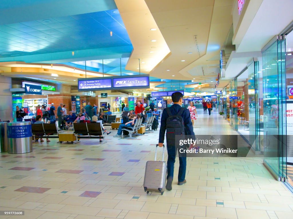 Business traveller with roller bag moving through airport terminal, Phoenix, AZ