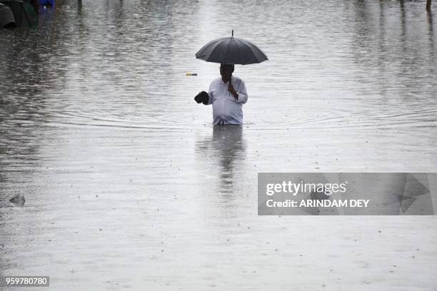 An Indian walks along a flooded street after a heavy downpour in Agatala, the capital of northeastern state of Tripura on May 18, 2018.