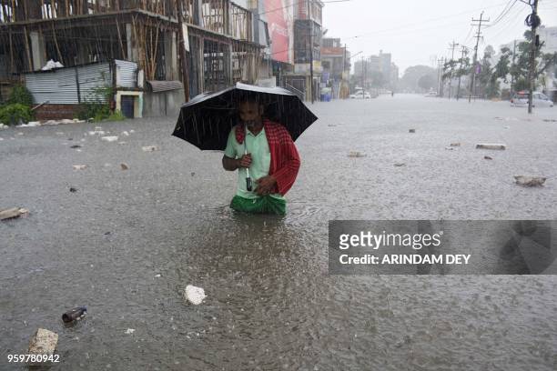 An Indian walks along a flooded street during a heavy downpour in Agatala, the capital of northeastern state of Tripura on May 18, 2018.