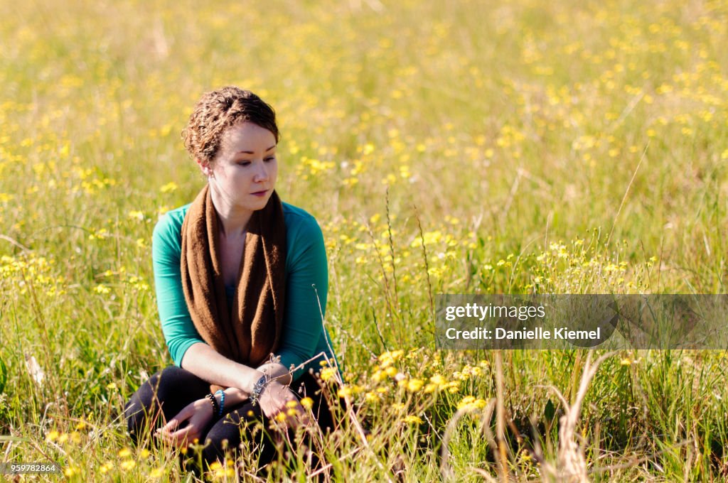 Young woman sitting in field of flowers