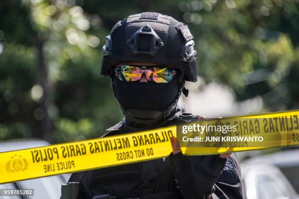 An anti-terror policeman gestures amid tight security at a hospital morgue, where the bodies of the individuals involved in the Surabaya suicide...