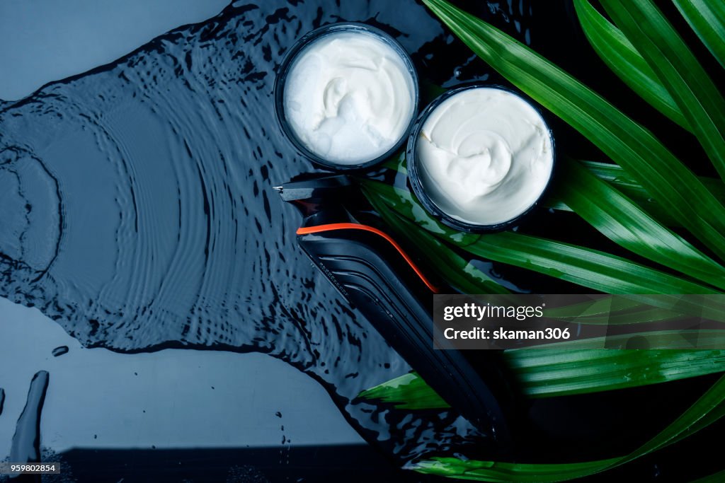 Top view beauty cream with green leaves and wet background