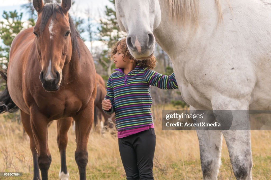 Mixed race girl connects with horses below mountains